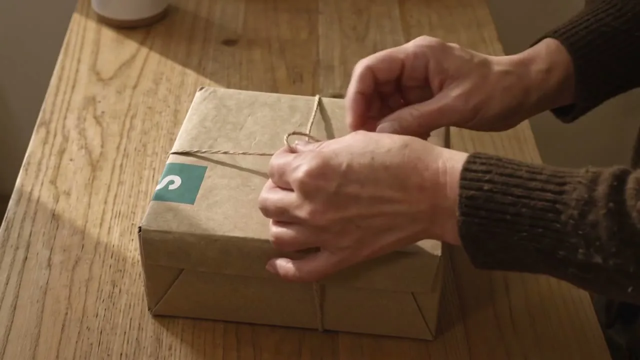 Schrankfund Premium-Verpackung mit gefalteten Kleidungsstücken, Paket mit Schrankfund-Banderole und Stoffbeutel mit Wordmark.